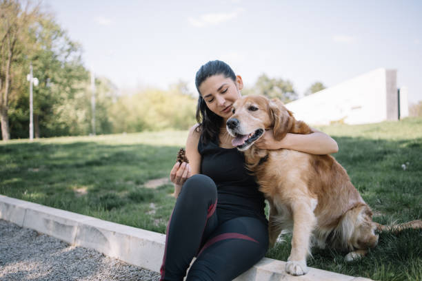 istock Young woman sitting on ground and hugging dog 1249156893