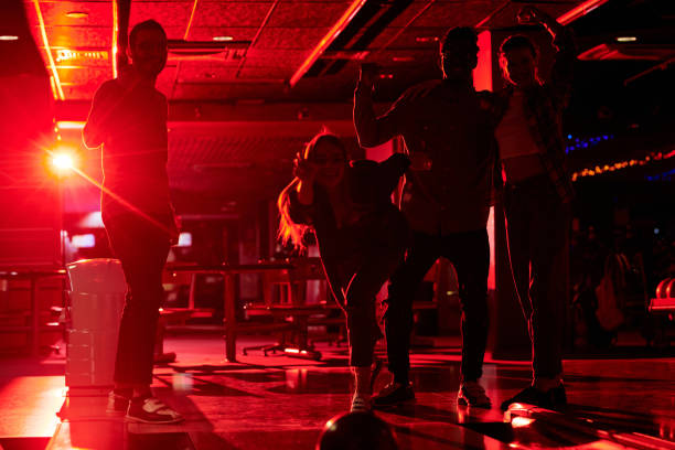 istock Happy young female throwing bowling ball while bending over track during game 1249160302