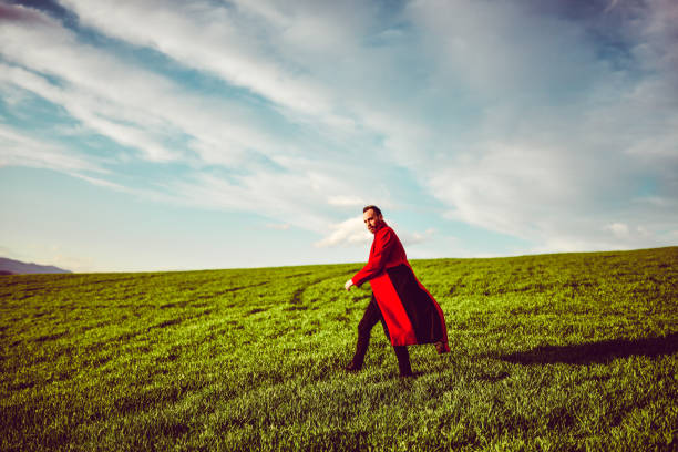 Male In Red Cloak Enjoying Beautiful Green Fields