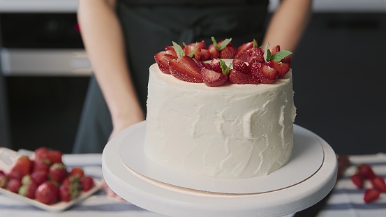 Cooking cake at home. Close up of beautiful white cake with strawberry on the top in a modern kitchen PHOTO