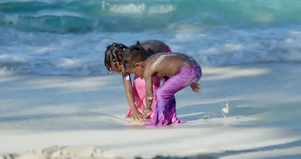 Mermaid children playing in the sand at a tropical beach in the Caribbean