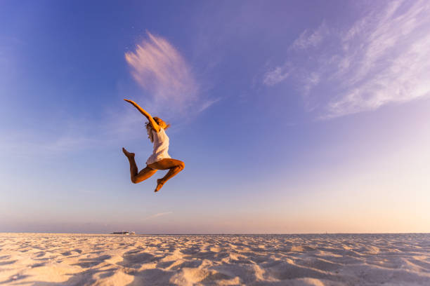 istock Carefree woman having fun while jumping on the beach. 1249171327