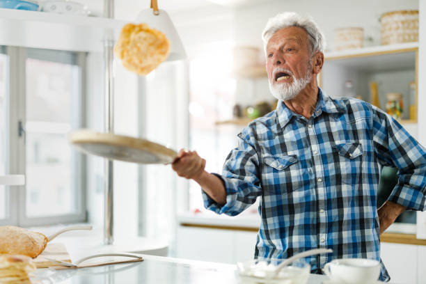 senior mann spaß beim pfannkuchen in der küche. - eierkuchen speise stock-fotos und bilder