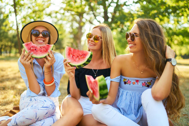 istock Three nice girls having fun eating watermelon In the park. 1249173574