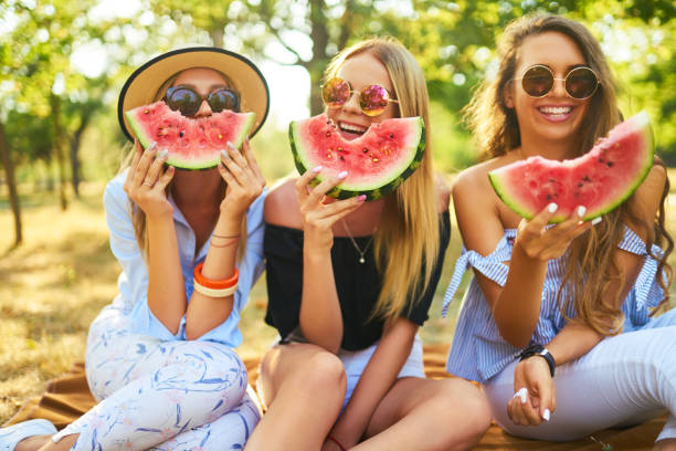 istock Three nice girls having fun eating watermelon In the park. 1249173603