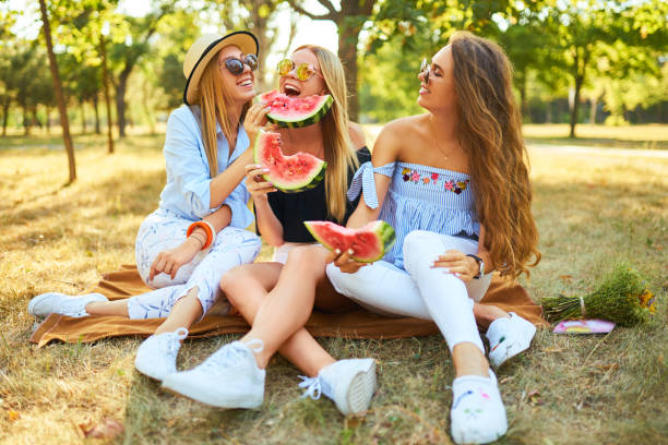 istock Three nice girls having fun eating watermelon In the park. 1249173608