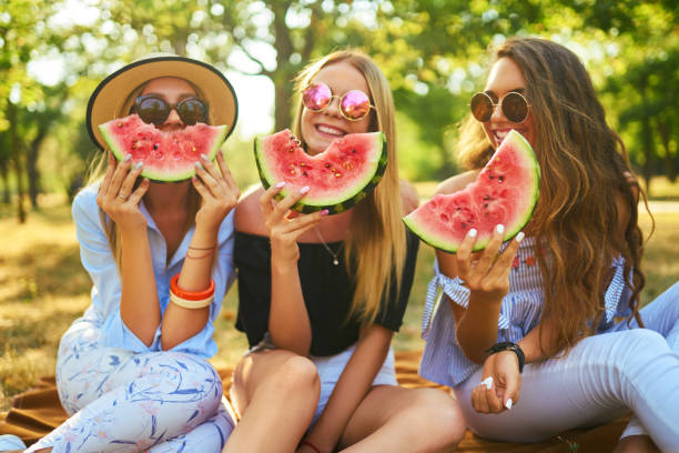 istock Three nice girls having fun eating watermelon In the park. 1249173610