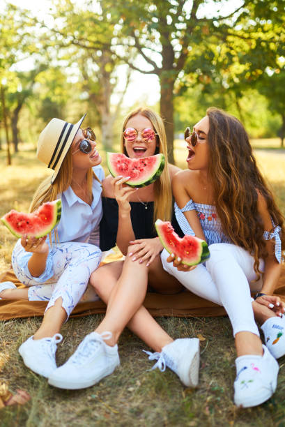 istock Three nice girls having fun eating watermelon In the park. 1249173611