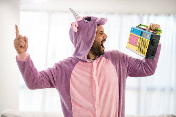 Playful man in unicorn costume singing along with radio music. Cheerful man in unicorn costume having fun while signing along with radio music at home. Unicorn stock pictures, royalty-free photos & images