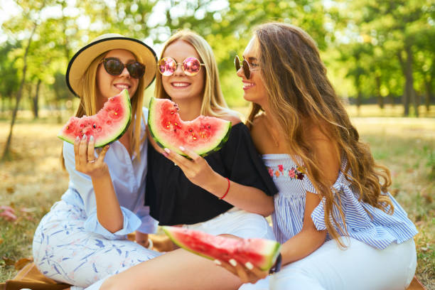 istock Three nice girls having fun eating watermelon In the park. 1249173638