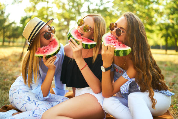 istock Three nice girls having fun eating watermelon In the park. 1249173644