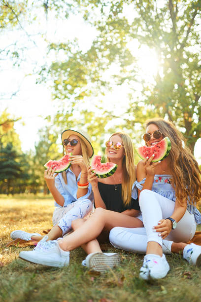 istock Three nice girls having fun eating watermelon In the park. 1249173651