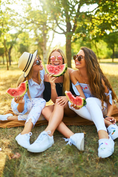 istock Three nice girls having fun eating watermelon In the park. 1249173675