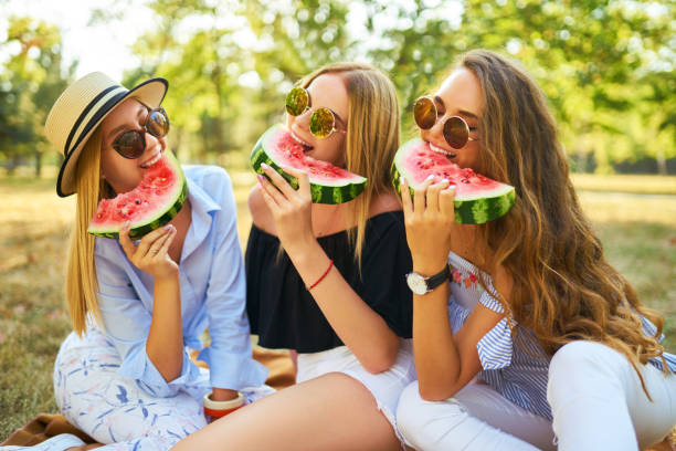 istock Three nice girls having fun eating watermelon In the park. 1249173706