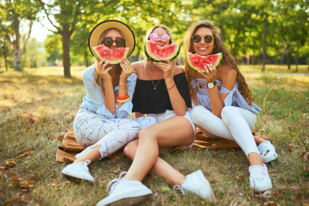 istock Three nice girls having fun eating watermelon In the park. 1249173716