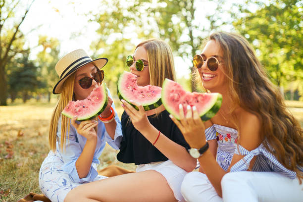 istock Three nice girls having fun eating watermelon In the park. 1249173739