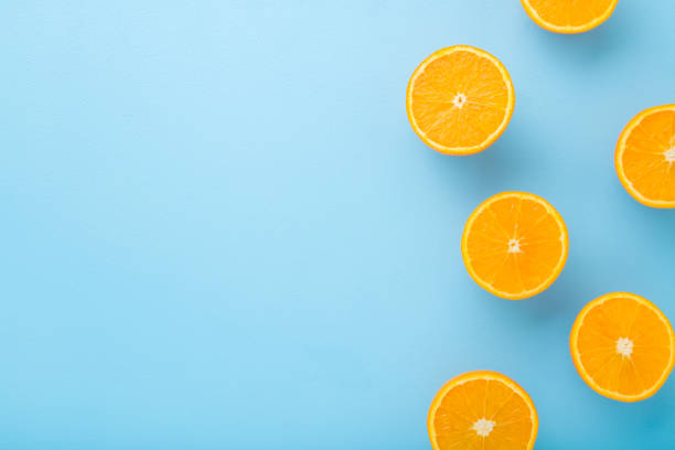 istock Bright halves of oranges. Fresh fruits. Empty place for text on light blue table background. Pastel color. Closeup. Top down view. 1249176111