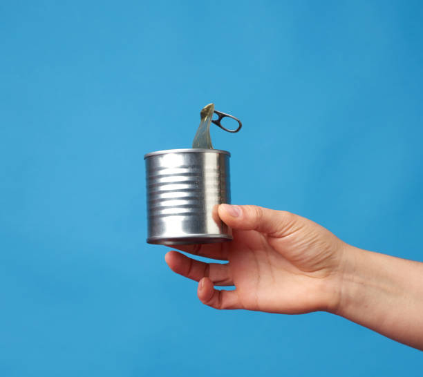 istock open metal round tin can in a female hand on a blue background 1249176527