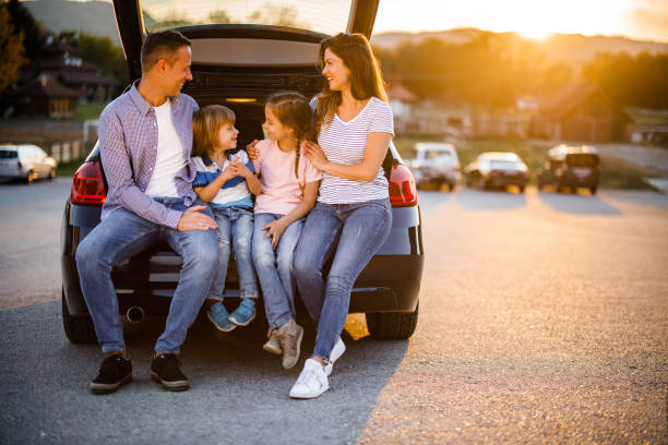 istock Young happy family talking on a car trunk at sunset. 1249176568