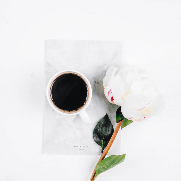 istock Coffee mug, notebook and white peony flowers on pink table background. Cozy, still life, minimal concept. Top view, flat lay, copy space 1249180186