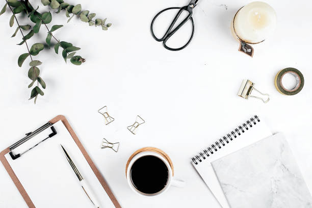Office table desk. Workplace with eucalyptus, clipboard, notebook, cup of coffee, scissors, candle and pen. Flat lay, top view, mockup, copy space. Blog, blogger concept
