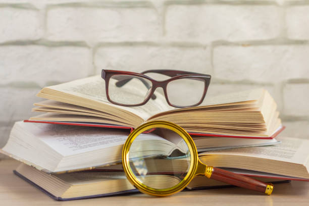 istock Several open books,glasses, and a magnifying glass on the table. 1249181830