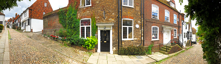 Mermaid Street, Rye, East Sussex, England. Panoramic wide angle view of Mermaid Street in the historic sea merchant trading town of Rye, now a picturesque traditional tourist destination with quaint houses and cobbled stone roads and alleyways.