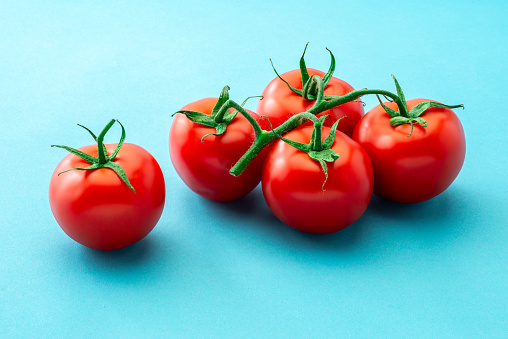 Vegetables:  five fresh juicy organic Tomatoes Isolated on blue Background.