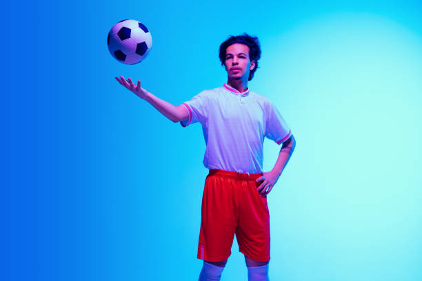 istock Football or soccer player on gradient background in neon light - motion, action, activity concept 1249186309