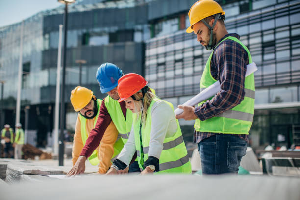 istock Engineers and architects looking at building blueprint at the construction site outdoors 1249189391