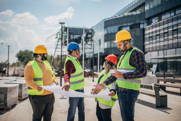 istock Engineers and architects looking at building blueprint at the construction site outdoors 1249189469