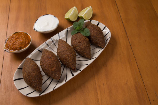 istock fried kibbeh served with yogurt sauce, lemon, and pepper sauce, on a plate 1249189924