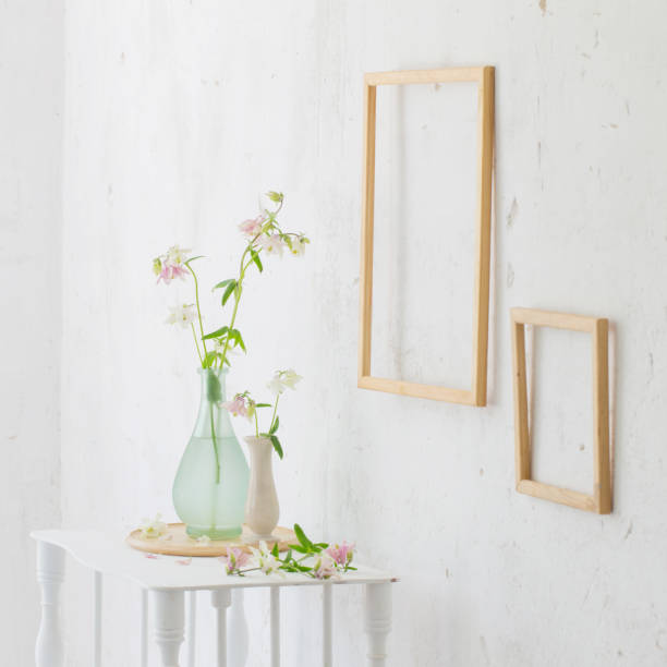 istock flowers in vase and wooden frames on white interior 1249193410
