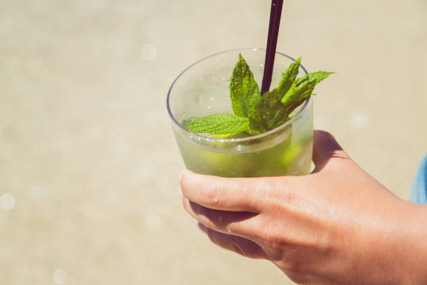 istock Hand holding mojito cocktail on the beach 1249195034