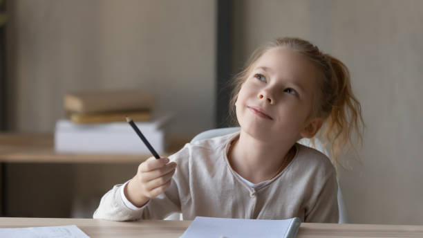 istock Dreamy small girl lost in thoughts distracted from studying 1249199807