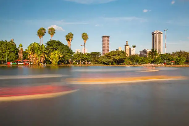 Long exposure of the skyline of Nairobi, Kenya with the beautiful lake in Uhuru Park in the foreground and some blurred boats.