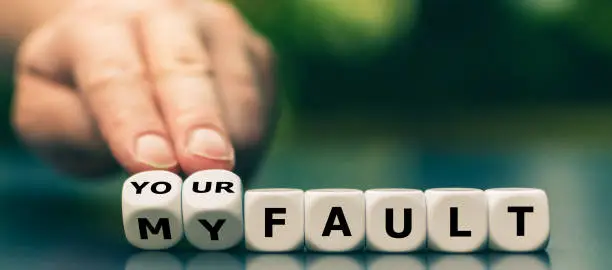 Hand turns dice and changes the expression "my fault" to "your fault".