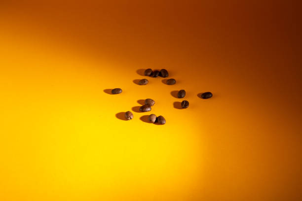istock Spilled roasted brown coffee beans isolated on yellow background, close up with copy space 1249202483