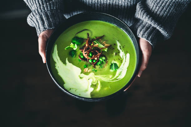 mão de mulher segurando um prato de sopa verde - pea and mint soup - fotografias e filmes do acervo