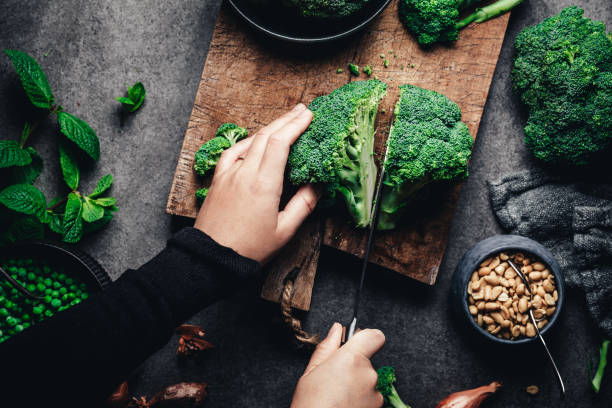 frau schneidet frischen brokkoli - kochen stock-fotos und bilder