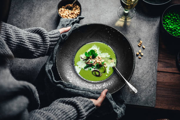 mulher com sopa de creme de ervilhas verdes recém-feita - pea and mint soup - fotografias e filmes do acervo