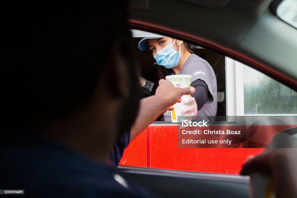 Drive Thru Prince Rupert, Canada - May 17, 2020. A man reaches for his food at the McDonalds drive-thru window as the employee wears a mask for protection. McDonald's Stock Photo