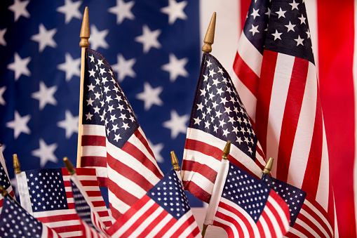 Background of large American Flag with many smaller American Flags in foreground.  Great background for American Flag Day, Memorial Day, 4th of July, Veterans Day or Sept 9 remembrance day.