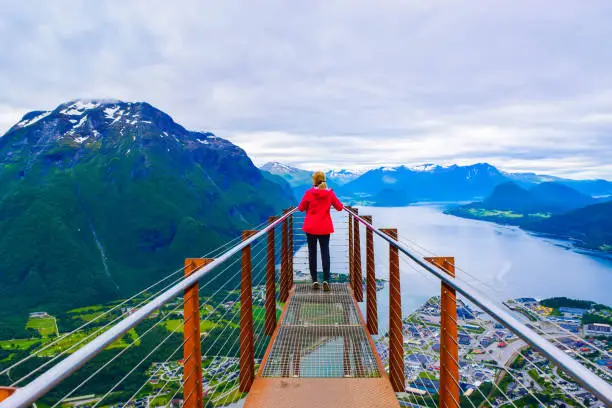 Hiking Rampestreken. Tourist girl on the Rampestreken Viewpoin. Panoramic landscape Andalsnes city located on shores of Romsdal Fjord between the picturesque mountains. Andalsnes. Norway.