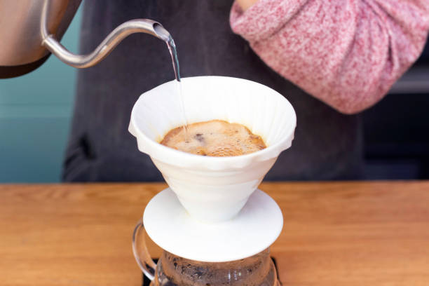 istock barista makes espresso using a funnel. The process of making coffee in the prover. Spilling coffee through the filter funnel from the kettle. 1249218019