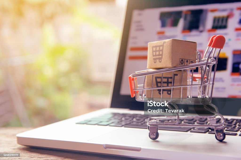 Shopping online concept - Parcel or Paper cartons with a shopping cart logo in a trolley on a laptop keyboard. Shopping service on The online web. offers home delivery. Online Shopping Stock Photo