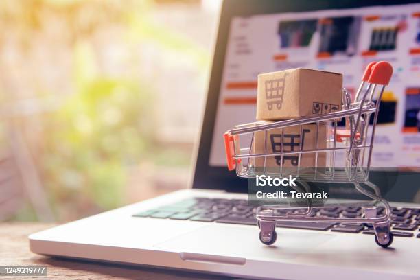 Shopping Online Concept Parcel Or Paper Cartons With A Shopping Cart Logo In A Trolley On A Laptop Keyboard Shopping Service On The Online Web Offers Home Delivery Stock Photo - Download Image Now