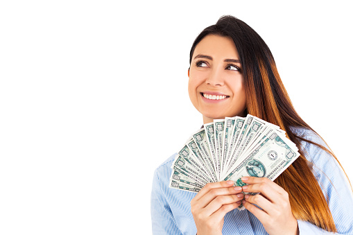 Young woman, holds bills with her hands. She is smiling and looking up. In the photo you see a copy space