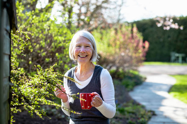 ritratto di donna anziana che si rilassa in giardino - planting clothing gray hair human age foto e immagini stock