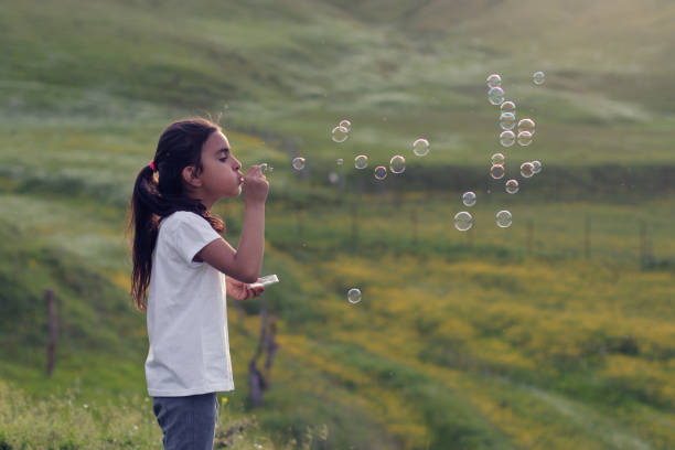 istock Little girl blowing soap bubbles 1249225935
